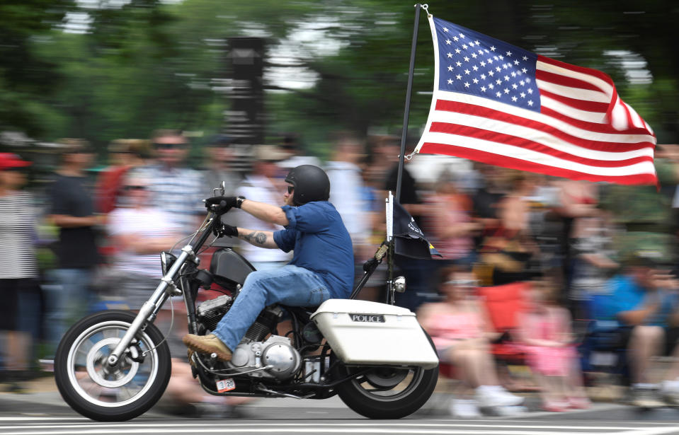 Un motard avec le drapeau américain flottant passe devant la foule lors du 32e Rolling Thunder 