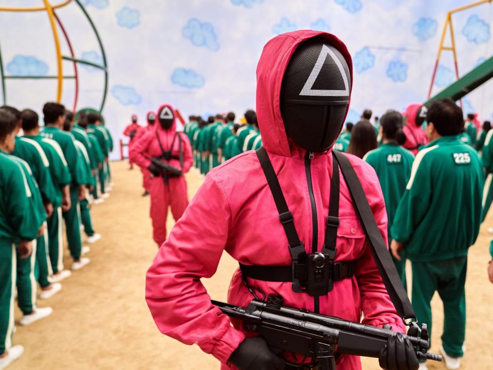 A triangle pink jacket with a gun in "Squid Game"