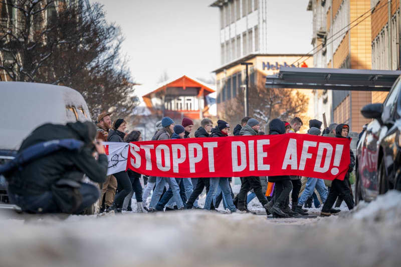 People walk with a banner reading "Stop the AfD!" during a demonstration at Erfurt Cathedral Square against right-wing extremism. Jacob Schröter/dpa