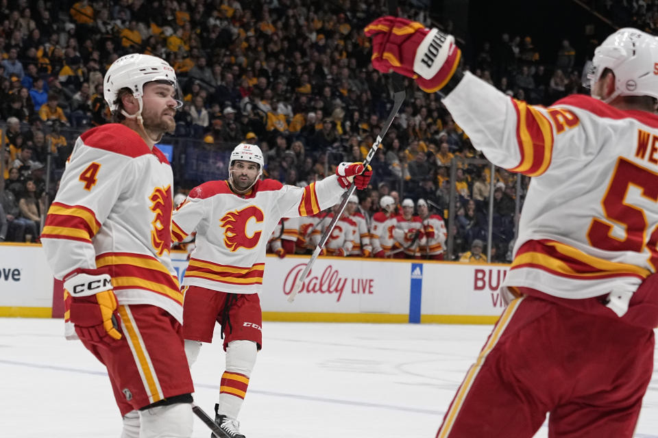 Calgary Flames defenseman Rasmus Andersson (4) is congratulated by center Nazem Kadri (91) and defenseman MacKenzie Weegar, right, after a goal against the Nashville Predators during the first period of an NHL hockey game Thursday, Jan. 4, 2024, in Nashville, Tenn. (AP Photo/George Walker IV)