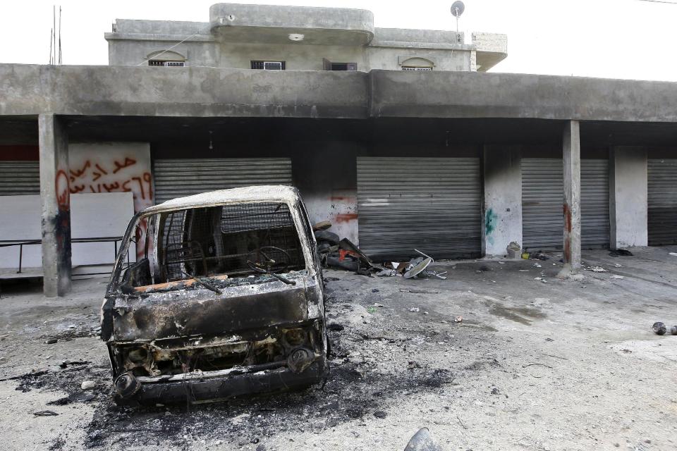 This picture taken on Monday, Feb. 24, 2014 shows the burned car of Hisham al-Mughayar, 45, the father of the suicide bomber Nidal al-Mughayar, which was torched as well as the family’s grocery shop and four vehicles by angry residents after the news spread in the village that Nidal was one of the two suicide attackers who carried out an attack in Beirut near the Iranian culture center, in the southern village of Bisariyeh, Lebanon. Nidal al-Mughayar renewed his travel document last year and told his family he will be leaving Lebanon to settle in Venezuela where there are more opportunities but it turned out later that the young Palestinian man called his family from Syria and it was only then that they knew he has joined jihadis fighting to overthrow President Bashar Assad’s government. (AP Photo/Mohammed Zaatari)