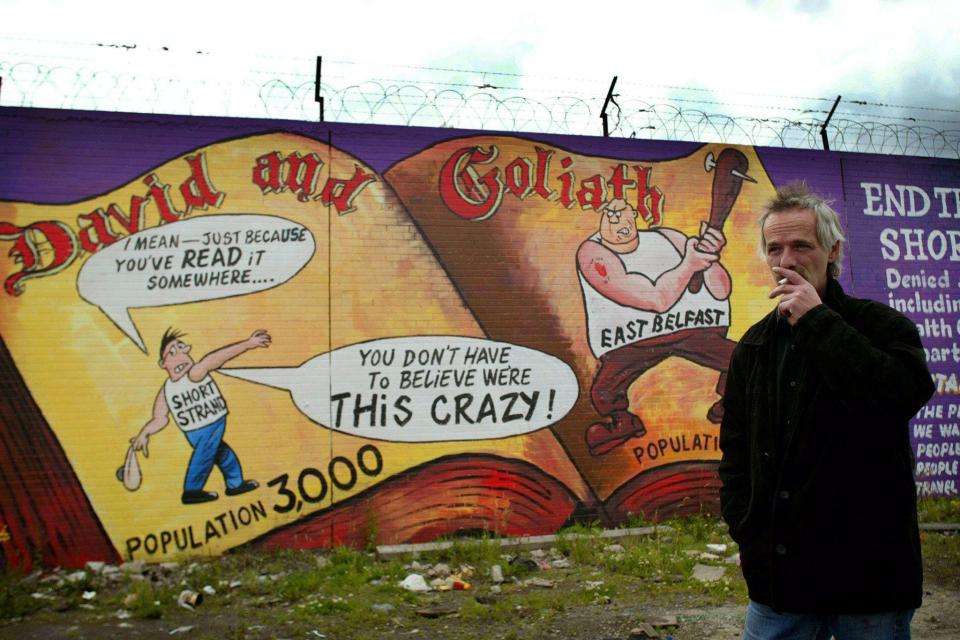 Danny Devenny stands in front of his work depicting nationalists as David and loyalists as Goliath in the Short Strand area of Belfast, July 2002Alamy