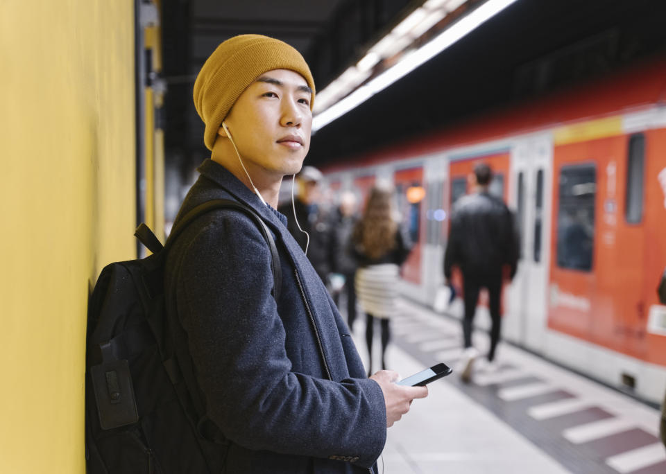 Someone listens to music while waiting for the subway