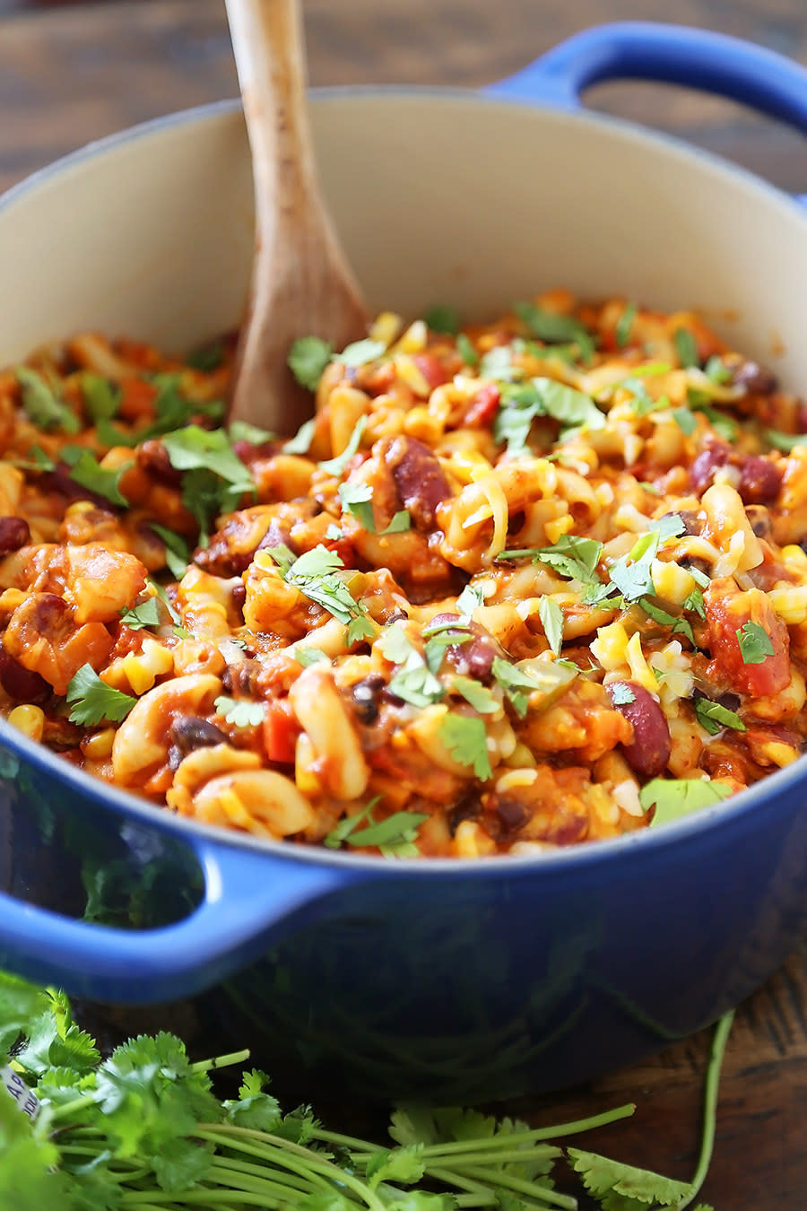 Vegetarian bean chili mac in a Dutch oven topped with herbs and cheese.