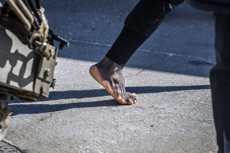 A migrant steps on the ground barefoot in the Sicilian port of Empedocle, Italy after being rescued by the Spanish NGO Open Arms in the the Mediterranean Sea, Tuesday, Feb 16, 2021. Various African migrants drifting in the Mediterranean Sea after fleeing Libya on unseaworthy boats have been rescued. In recent days, the Libyans had already thwarted eight rescue attempts by the Open Arms, a Spanish NGO vessel, harassing and threatening its crew in international waters. (AP Photo/Bruno Thevenin)