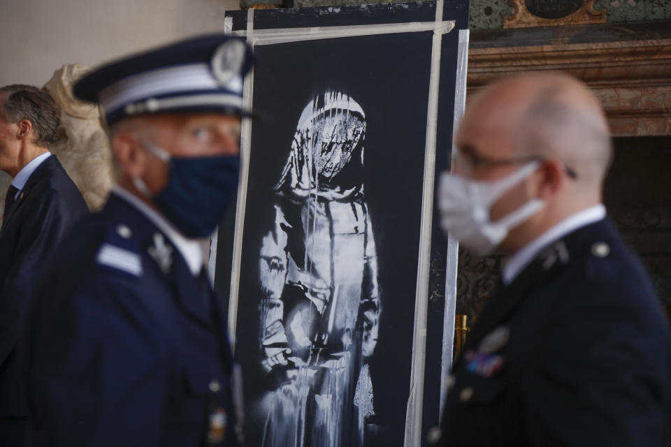 A recovered stolen artwork by British artist Banksy, depicting a young female figure with a mournful expression, that was painted as a tribute to the victims of the 2015 terror attacks at the Bataclan music hall in Paris, is shown during a ceremony at the French Embassy in Rome, Tuesday, July 14, 2020. The work was recovered last June 10 during a search of a home in Tortoreto, a city near the Adriatic coast in the Abruzzo region’s Teramo province. (AP Photo/Domenico Stinellis)