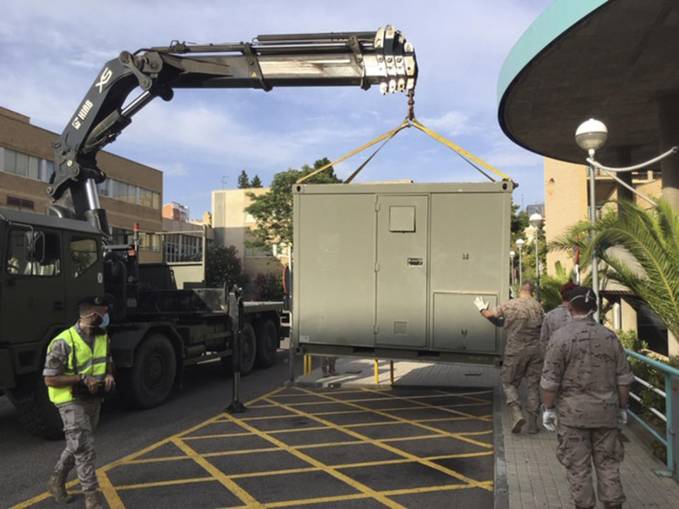 In this photo provided by the Spanish Ministry of Defence, soldiers install modules in the car park of the Hospital Clinico Universitario in Zaragoza, Spain, Tuesday Aug. 11, 2020. Spain's army is setting up a field hospital in Zaragoza as the northern city struggles to stop a new spike in cases of the coronavirus. The region of Aragon, home to Zaragoza, has led Spain over the past seven days with over 200 people hospitalized and over 30 deaths from COVID-19. (MDE via AP)