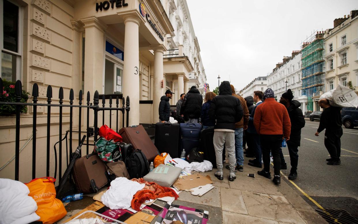 Migrants with their bags and suitcases outside the Comfort Inn in Pimlico - Jamie Lorriman for The Telegraph