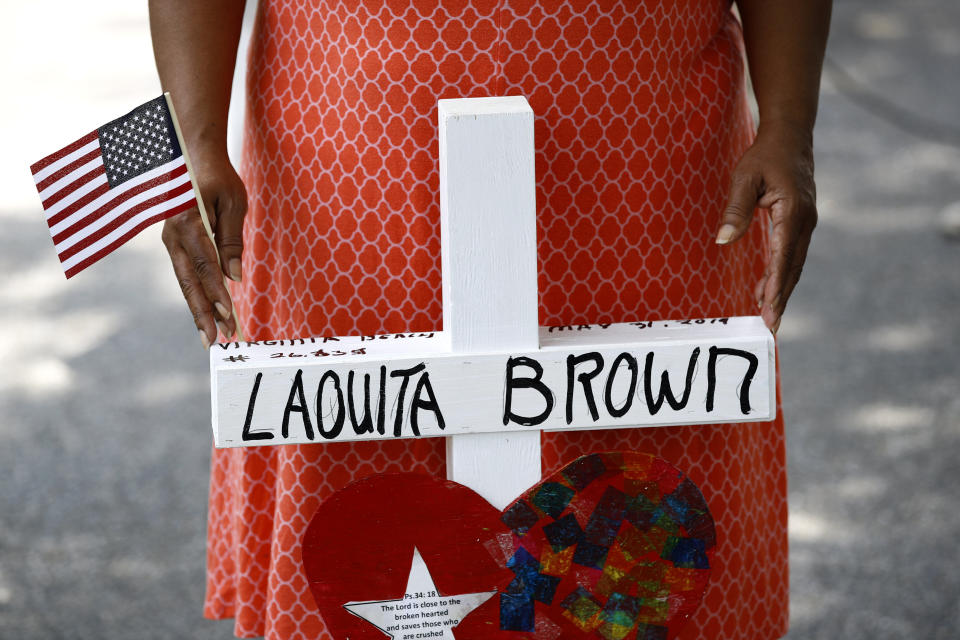 Patricia Olds rests her hands on a cross bearing the name of Olds' coworker, LaQuita Brown, a victim of a mass shooting at a municipal building in Virginia Beach, Va., before carrying the cross to a nearby makeshift memorial, June 2, 2019. (Photo: Patrick Semansky/AP)
