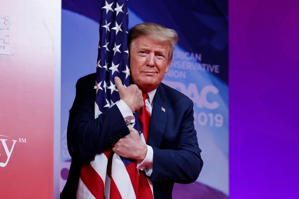 President Donald Trump hugs the American flag as he arrives to speak at Conservative Political Action Conference, CPAC 2019, in Oxon Hill, Md., March 2, 2019.