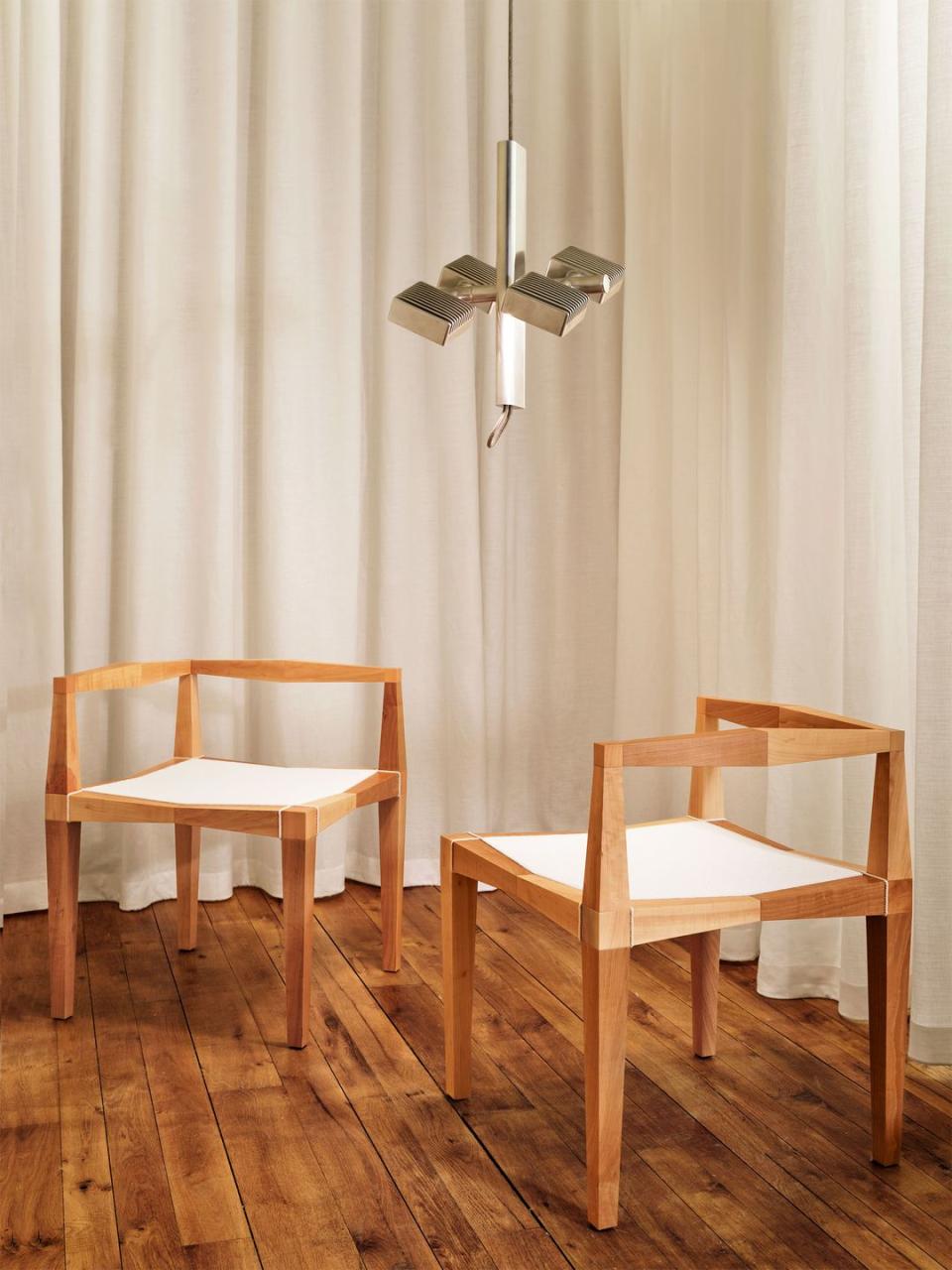 two very square wood chairs in front of a curtain