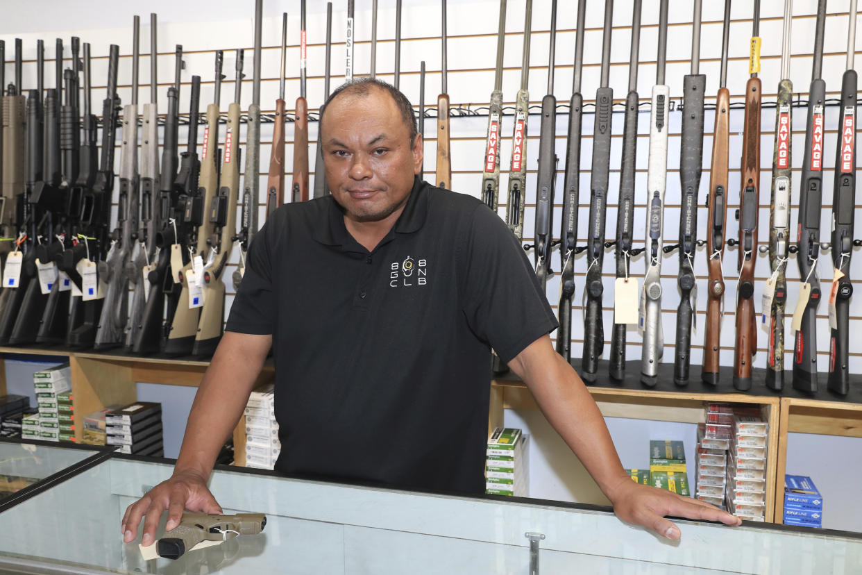Tom Tomimbang, managing partner at the 808 Gun Club, shows off several small handguns inside his shop, Thursday, June, 23, 2022 in Honolulu. (AP Photo/Marco Garcia)