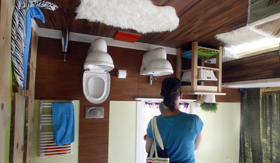 A woman stands inside the bathroom of a house, which was built upside down by Polish architects Irek Glowacki and Marek Rozhanski, in the western Austrian village of Terfens May 5, 2012. The project is meant to serve as a new tourist attraction in the area, and is now open for public viewing. Picture taken May 5, 2012. REUTERS/Dominic Ebenbichler (AUSTRIA - Tags: SOCIETY TRAVEL) - RTR31O4K