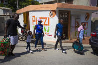 Jhon Celestin, second right, his wife Delta De Leon and their daughter Chloe, deported fron the United States a few days earlier, walk to a bus station in Port-au-Prince, Haiti, Friday, Sept. 24, 2021. De Leon intends to cross the border into the Dominican Republic with her daughter as soon as possible to reunite with her father, sister and brother while her husband flies ahead to Chile. But first, the family will travel to the coastal city of Jacmel in southern Haiti to see more relatives, a risky trip because it entailed crossing gang-controlled territory. (AP Photo/Joseph Odelyn)