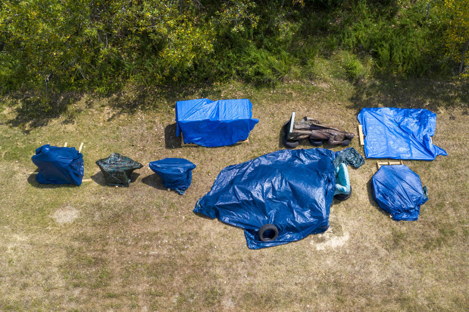 Confederate statues are covered in tarps while being stored at a waste water treatment plant near downtown Tuesday July 14, 2020, in Richmond, Va. The city of Richmond removed several of the statues along Monument Ave. where they will be stored until suitable sites can be found for them. (AP Photo/Steve Helber)