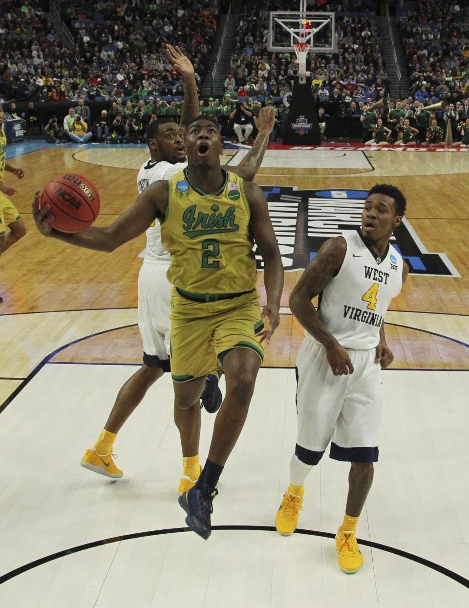 <p>Notre Dame guard Temple Gibbs (2) goes to the basket against West Virginia forward Elijah Macon (45) and guard Daxter Miles Jr. (4) during the first half of a second-round men’s college basketball game in the NCAA Tournament, Saturday, March 18, 2017, in Buffalo, N.Y. (AP Photo/Bill Wippert) </p>