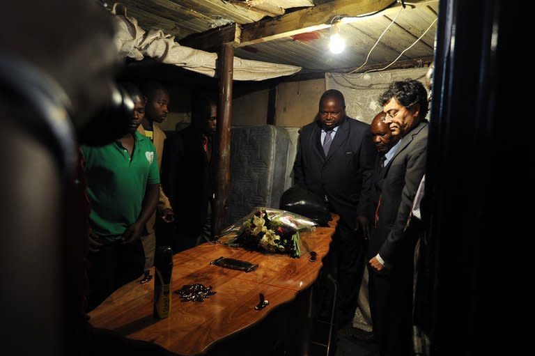 Josehp Macia (C), father of Mido Macia, looks at his son's coffin at his home in Daveyton, on March 8, 2013. Mourners in Mozambique gathered on Saturday for the funeral of Macia who died in police custody in South Africa after officers cuffed him to their van and dragged him through the streets