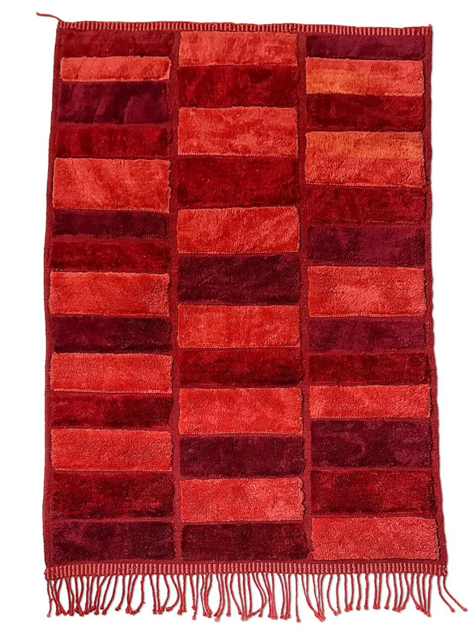 fringed plush rug in blocks of varying colors of red