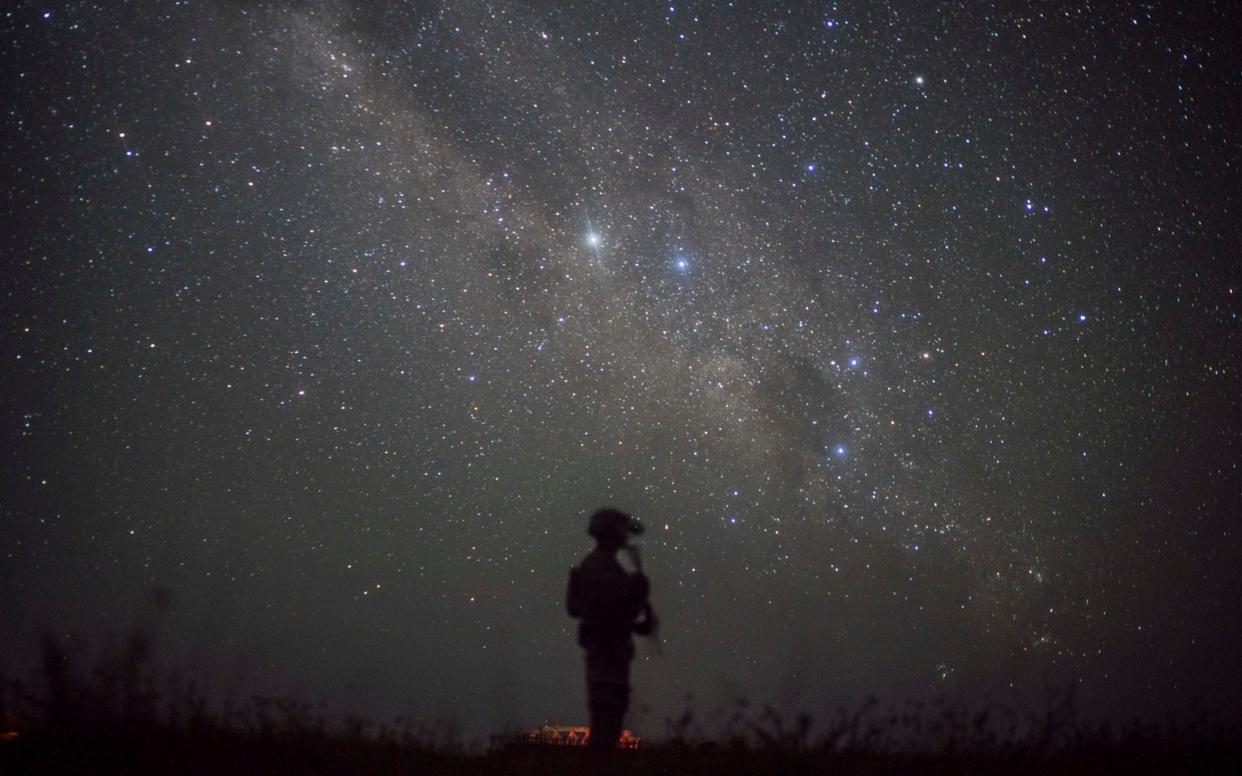 A US soldier assigned as part of a site security team in Somalia is seen silhouetted at night against a starry sky - Staff Sgt. Shawn White/Combined Joint Task Force, Horn of Africa via AP