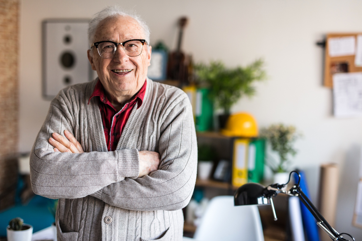 Happy senior man standing with his arms folded