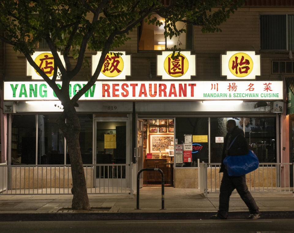 FILE - In this late Thursday, Dec. 17, 2020, file photo, a man walks past the outside of Yang Chow restaurant in Los Angeles. Congress’ $900 billion pandemic relief package, which passed Monday, Dec. 21, 2020, includes a $600 direct stimulus payment to most Americans and a new round of subsidies for hard-hit businesses, restaurants and theaters. (AP Photo/Damian Dovarganes, File)