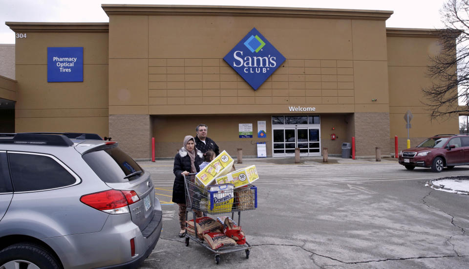 Shoppers wheel their cart to their car in the parking lot of a Sam's Club store in Concord, N.H., Friday, Feb. 23, 2018. (AP Photo/Charles Krupa)