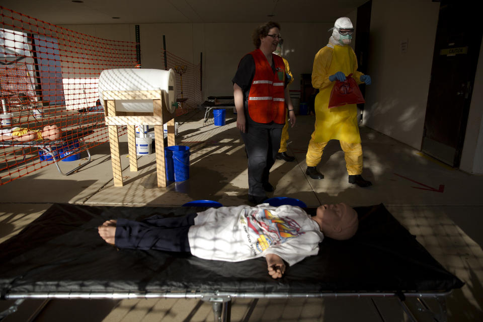 Sharon Roy, of the CDC, left, and licensed clinician Dennis Salter, right, deliver simulation contaminated bags to a biohazard bin on Monday, Oct. 6, 2014, in Anniston, Ala. The Centers for Disease Control and Prevention (CDC) has developed an introductory training course for licensed clinicians. According to the CDC, the course is to ensure that clinicians intending to provide medical care to patients with Ebola have sufficient knowledge of the disease. (AP Photo/Brynn Anderson)