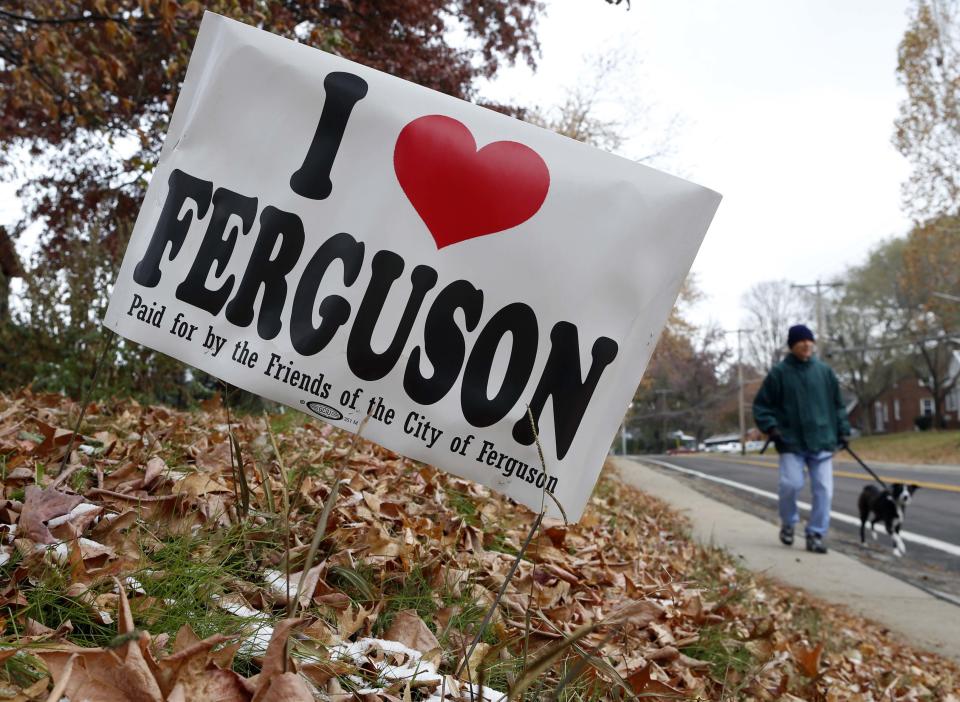 A man is pictured past a "I Love Ferguson" sign as he walks his dog down a street in Ferguson