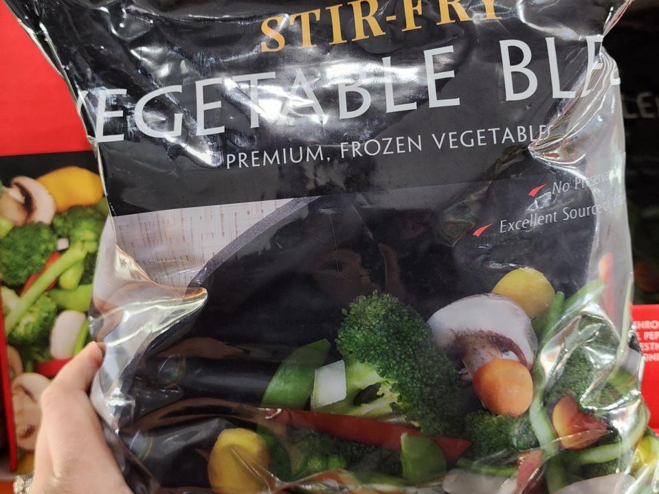 The writer holds a bag of frozen vegetable sit-fry