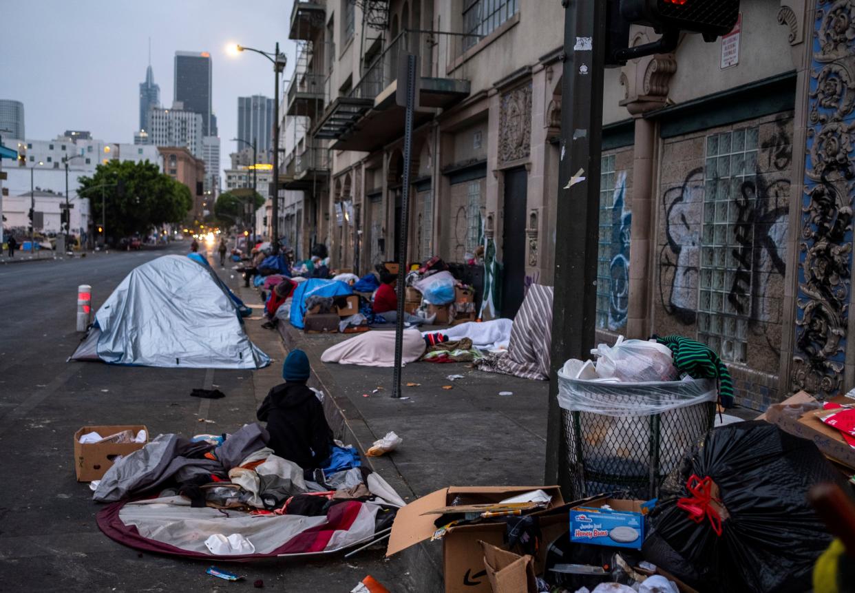 As the sun starts to rise at dawn people start to wake up and move around in skid row on Wednesday, May 12, 2021 in Los Angeles, CA (Francine Orr/Los Angeles Times/Shutterstock)