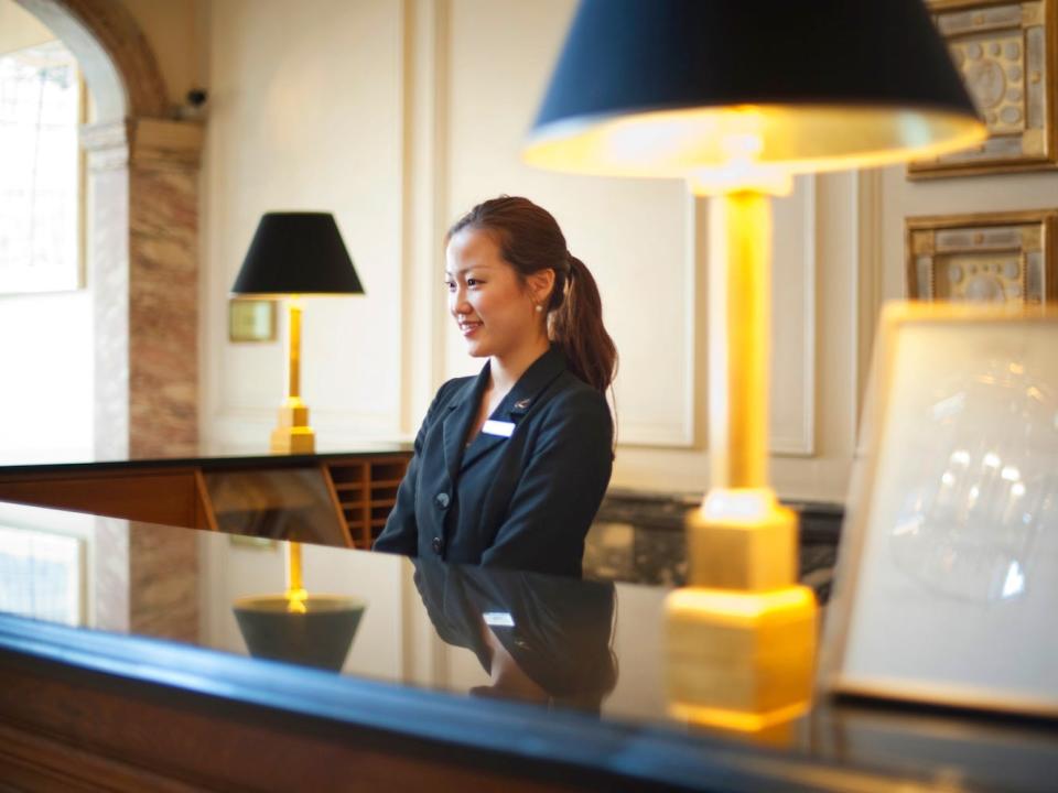 A person stands at the desk of a hotel lobby.