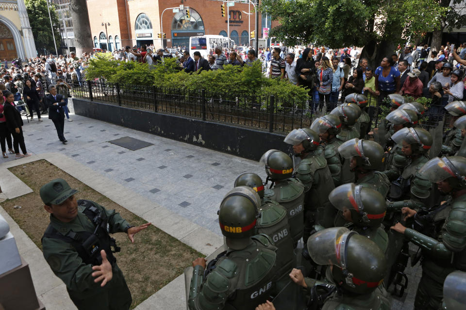 National Guards stand in formation at the entrance to the National Assembly grounds to block opposition lawmakers, including Henry Ramos Allup, top left, from entering to attend a session in Caracas, Venezuela, Tuesday, Jan. 7, 2020. Opposition leader Juan Guaidó and lawmakers who back him pushed their way into the legislative building on Tuesday following an attempt by rival legislators to take control of the congress, and declared Guaidó the president of the only opposition-controlled institution. (AP Photo/Andrea Hernandez Briceño)