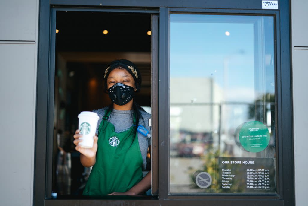 A Starbucks employee holds a drink up while working the drive through counter at Starbucks.