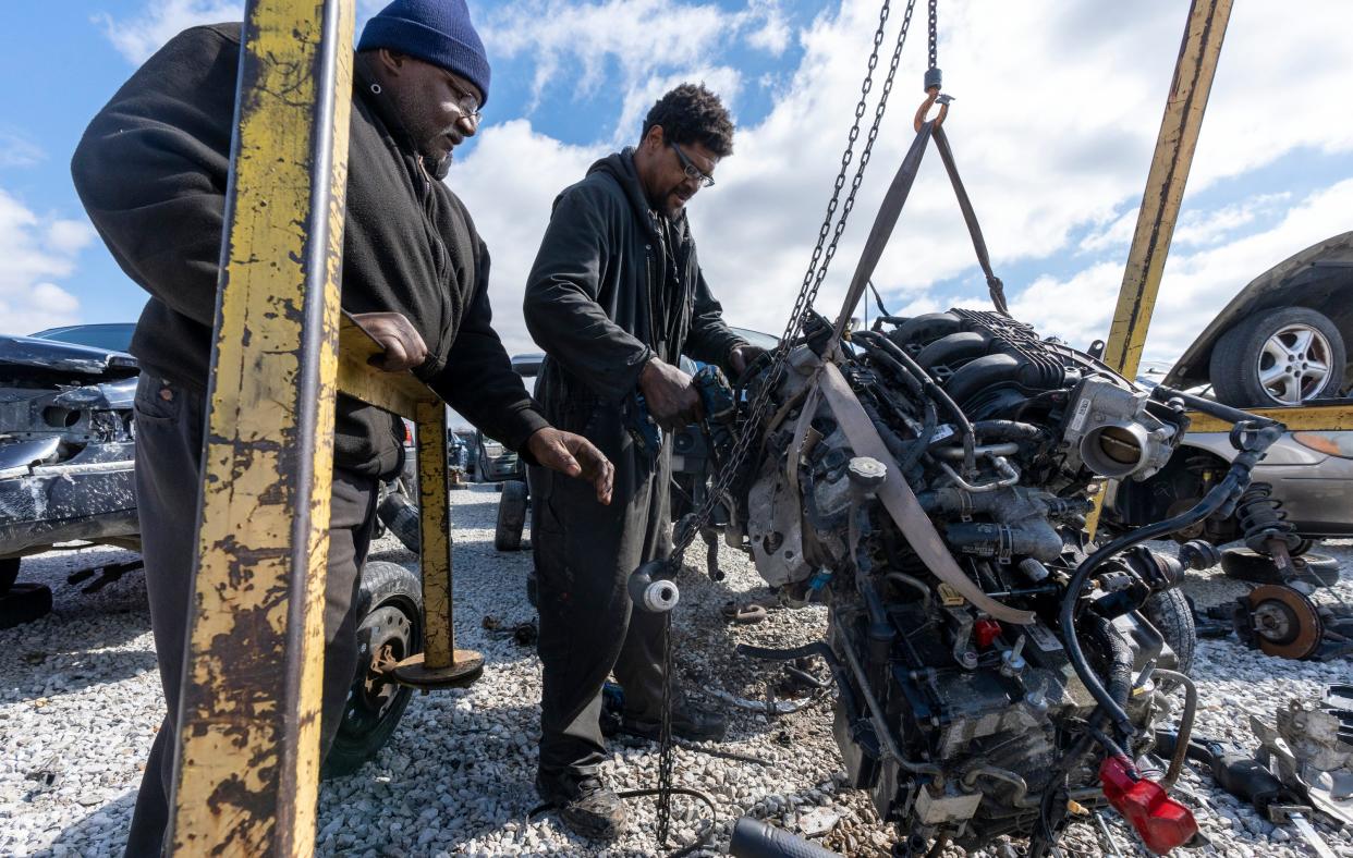 Carl Rice (left), watches his cousin Phillip Rice, both of Indianapolis, as he works at removing parts off a salvaged engine in the Martindale-Brightwood neighborhood of Indianapolis, Tuesday, March 7, 2023, at Pull-A-Part, a national chain of do-it-yourself auto salvage facilities. 