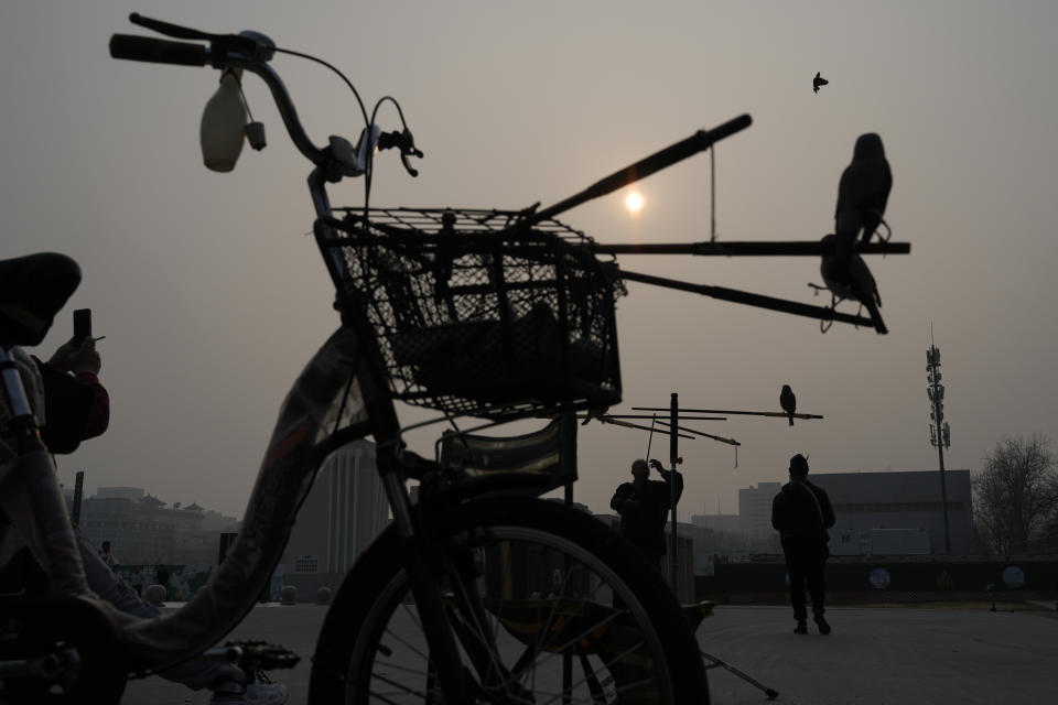 A man blows a bead out of a tube for a bird to catch in mid-air, practising a Beijing tradition that dates back to the Qing Dynasty, outside a stadium in Beijing, Tuesday, March 26, 2024. Today, only about 50-60 people in Beijing are believed to still practice it. (AP Photo/Ng Han Guan)