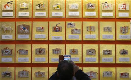 A man takes pictures of "Ema", small wooden plaques, displayed at Yasukuni Shrine in Tokyo January 1, 2014. REUTERS/Yuya Shino