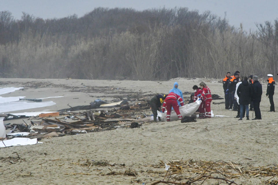 Rescuers recover a body after a migrant boat broke apart in rough seas, at a beach near Cutro, southern Italy, Sunday, Feb. 26, 2023. Rescue officials say an undetermined number of migrants have died and dozens have been rescued after their boat broke apart off southern Italy. (AP Photo/Giuseppe Pipita)