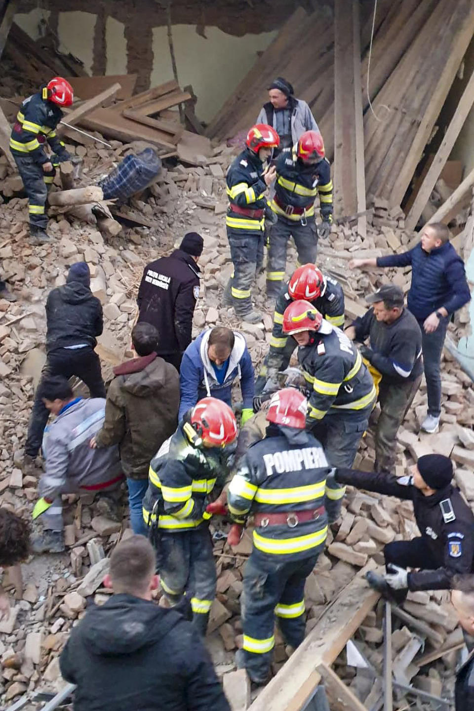 In this photo released by the Romanian Emergency Services Harghita (ISU Harghita), firefighters carry a survivor recovered from a collapsed section of a boarding school in Odorheiul Secuiesc, Romania, Monday, Dec. 18, 2023. The partial collapse of a boarding school in central Romania on Monday left one person dead and three injured, one seriously, authorities said. (Romanian Emergency Services - ISU Harghita via AP)