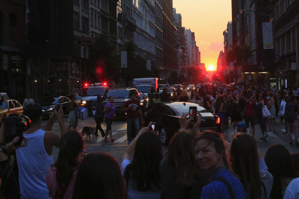 People take pictures at sunset, during the bi-annual occurrence "Manhattanhenge" in New York