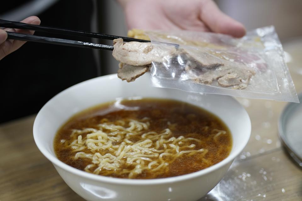 A staff member cooks one of their ramen merchandise sold online at Gourmet Innovation in Tokyo, on April 10, 2024. Gourmet Innovation has signed on 250 of the country's top ramen joints to sell packaged versions of their soup, noodles and toppings, to be heated up in boiling water and served at home. (AP Photo/Eugene Hoshiko)