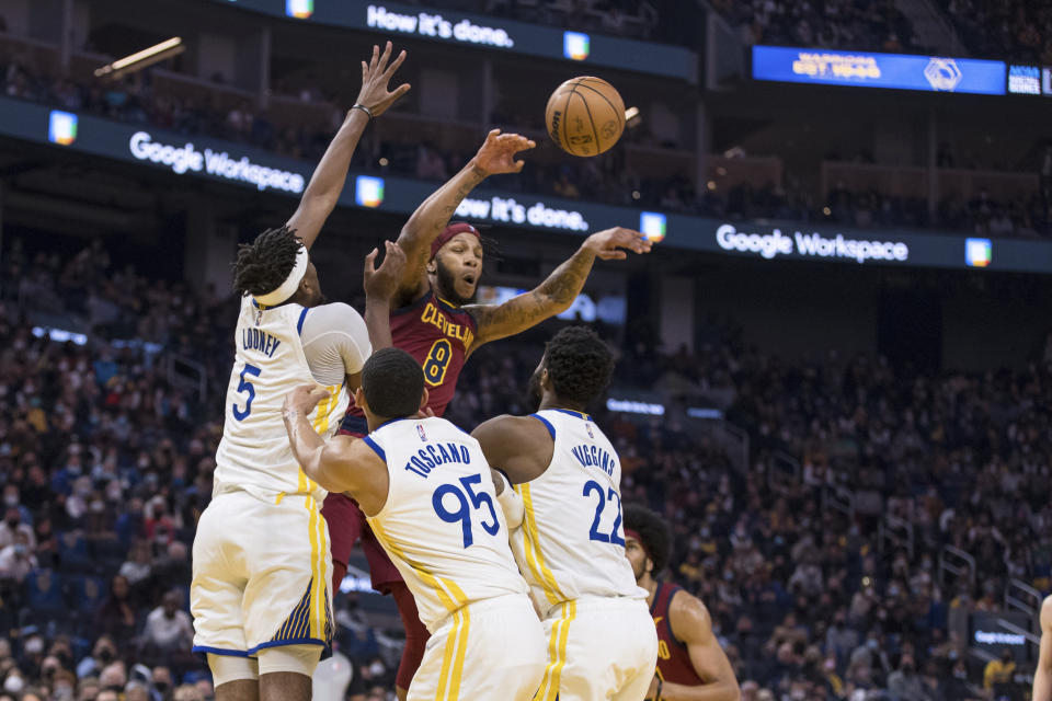 Cleveland Cavaliers forward Lamar Stevens (8) passes the ball over Golden State Warriors forward Andrew Wiggins (22), forward Juan Toscano-Anderson (95) and center Kevon Looney (5) during the first half of an NBA basketball game in San Francisco, Sunday, Jan. 9, 2022. (AP Photo/John Hefti)