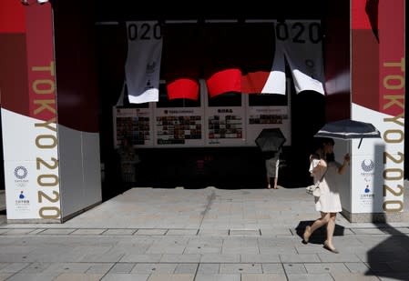 Passersby holding sunshades walk past decorations celebrating the upcoming Tokyo 2020 Olympic and Paralympic Games at Nihonbashi district in Tokyo