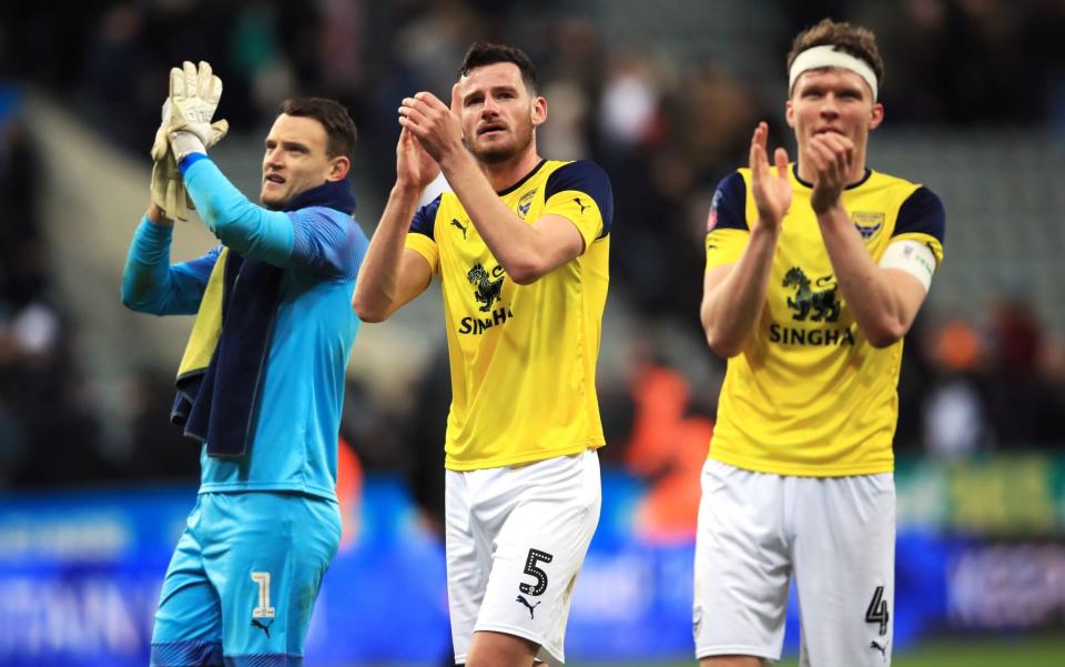 Oxford United players celebrate their 0-0 draw at St James' Park over a side two divisions ahead of them  - PA