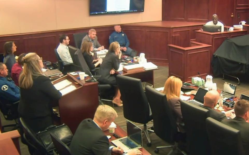 Prosecutor Lisa Teesch-Maguire, standing left, questions witness Derick Spruel on Tuesday while James Holmes, seated far left, watches. (AP, Pool)