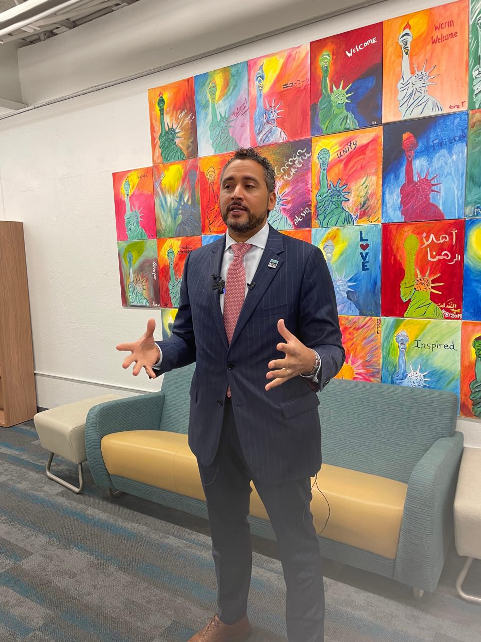 New York Secretary of State Robert J. Rodriguez addresses reporters in front of a mural at The Center.