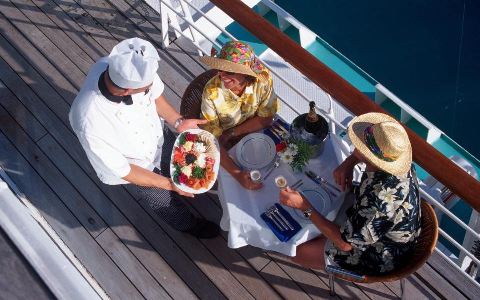 Couple served meal on deck by waiter - Barry Winiker/Getty