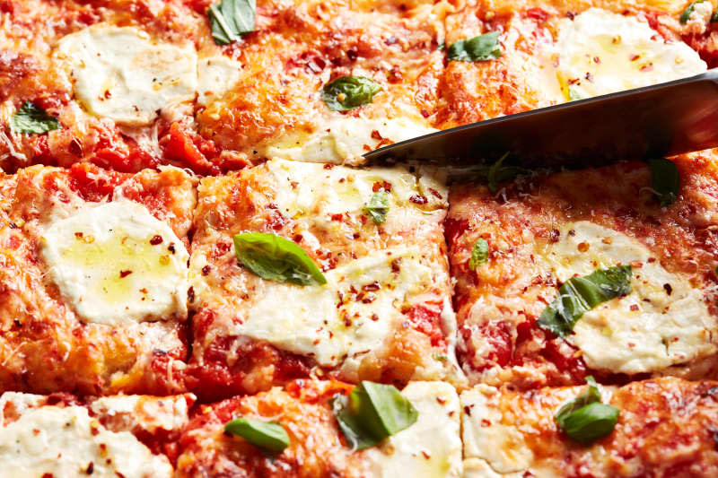 Knife slicing into focaccia pizza.