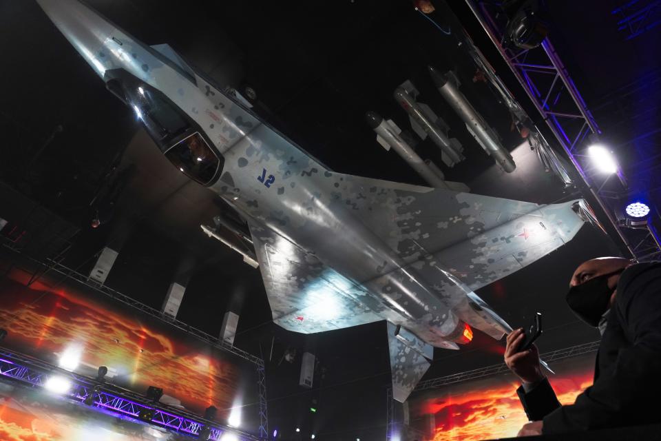 Russian officials unveil a mockup of the Sukhoi Su-75 Checkmate stealth fighter jet, a competitor to the American F-35, reflected in the ceiling, at the Dubai Air Show in Dubai, United Arab Emirates, Sunday, Nov. 14, 2021. The biennial Dubai Air Show opened Sunday as commercial aviation tries to shake off the coronavirus pandemic. (AP Photo/Jon Gambrell)