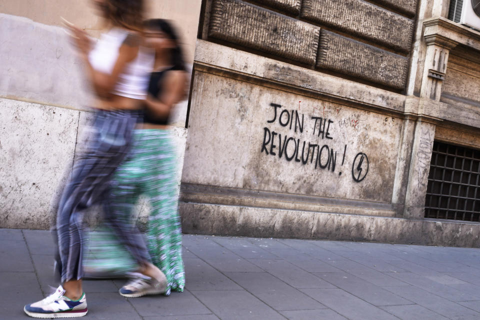 People walk past a mural by right-wing students movement called "Blocco Studentesco" (Student Block) in downtown Rome, Sunday, Aug. 13 ,2023. When Giorgia Meloni was running to become Italy’s first far-right head of government since the demise of the country's fascist dictatorship, she steeped her campaign in ideological touchpoints like national sovereignty and “traditional families.” (AP Photo/Gregorio Borgia)