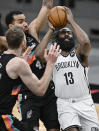 Brooklyn Nets' James Harden (13) attempts to shoot as he is defended by San Antonio Spurs' Trey Lyles (41) and Jakob Poeltl during the second half of an NBA basketball game, Monday, March 1, 2021, in San Antonio. (AP Photo/Darren Abate)